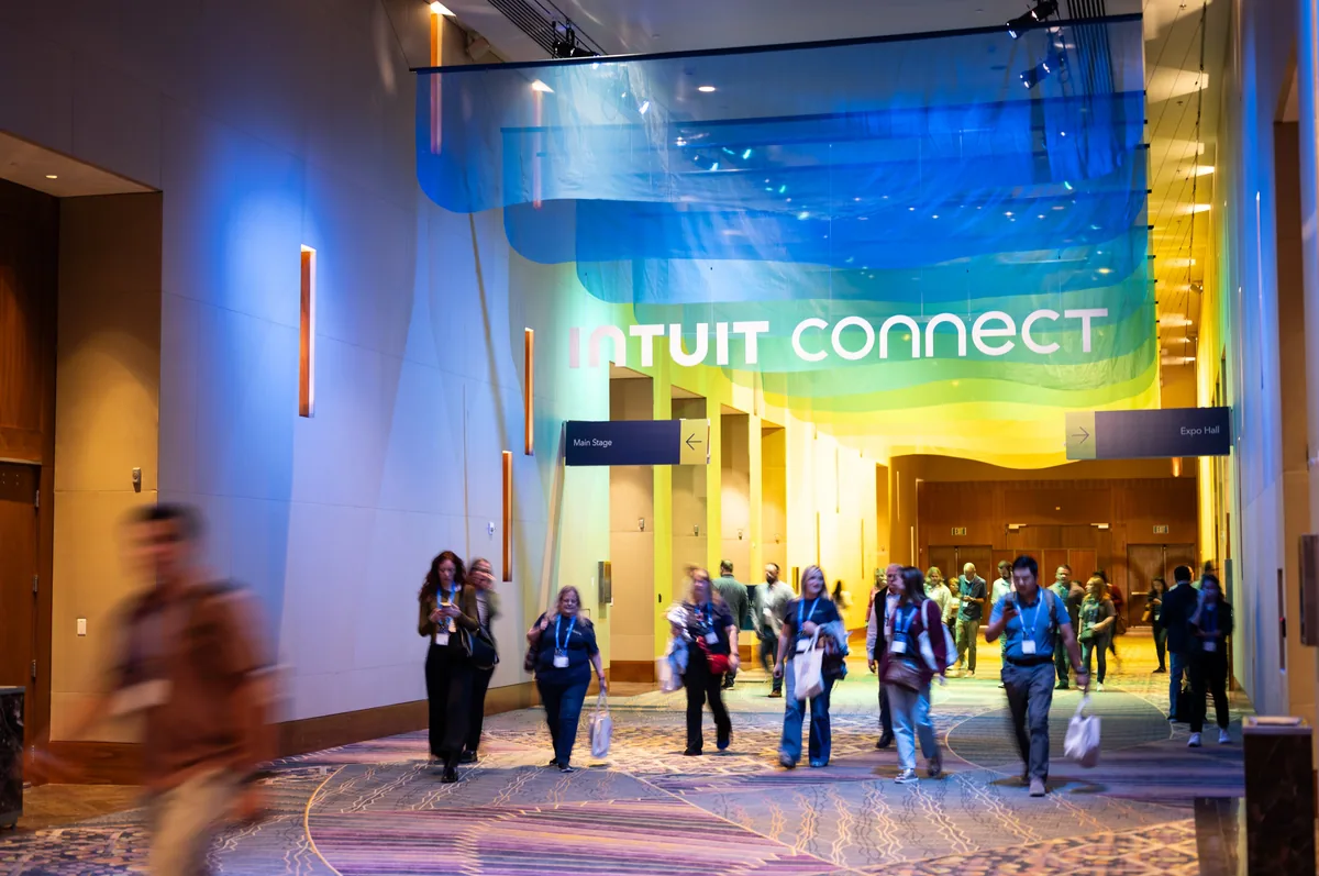Attendees walking beneath a glowing Intuit Connect arch