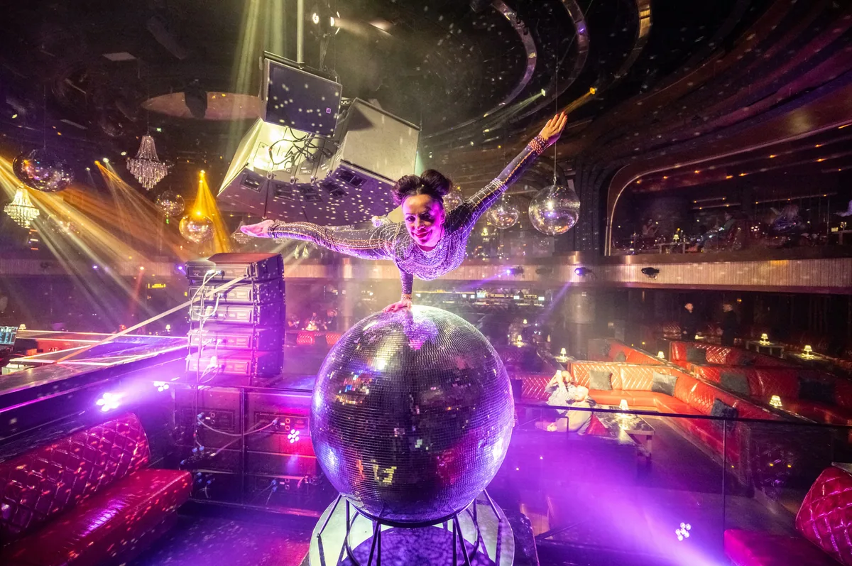 Performer dancing on a mirrored disco ball